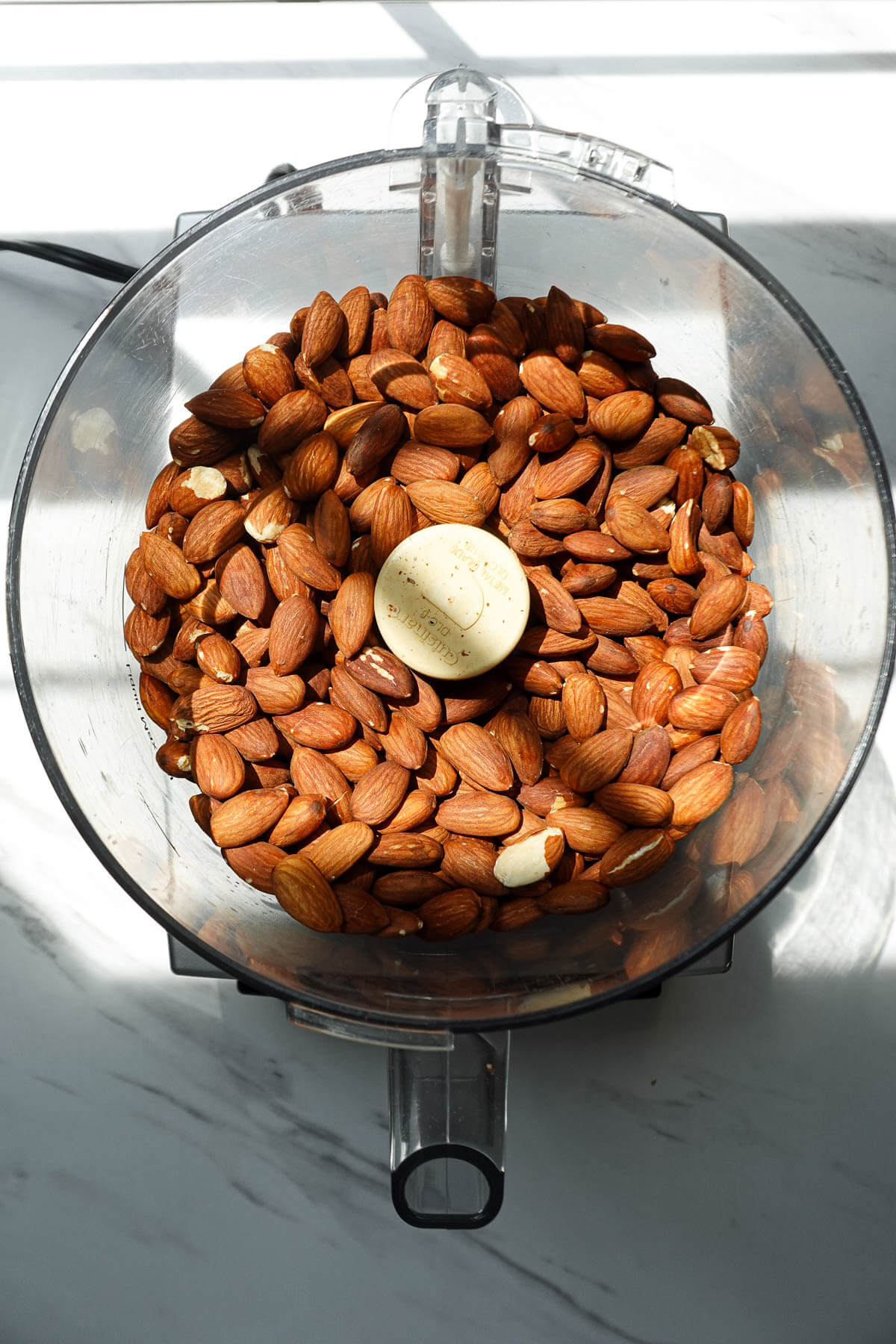 Roasted almonds in a food processor before blending into almond butter.