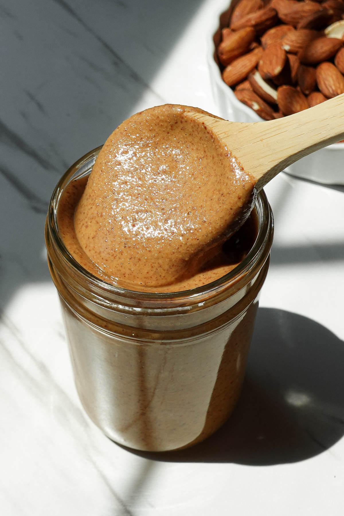 Homemade almond butter spooned into a glass storage jar.