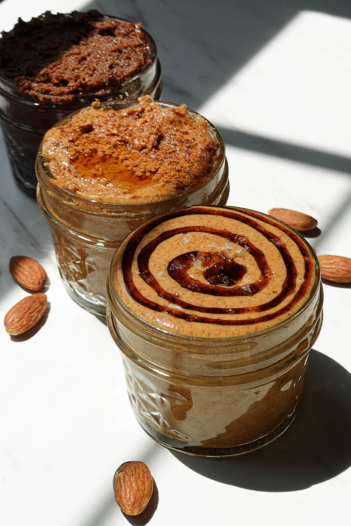3 jars with different almond butter flavors including salted vanilla, maple cinnamon, and chocolate almond butter.