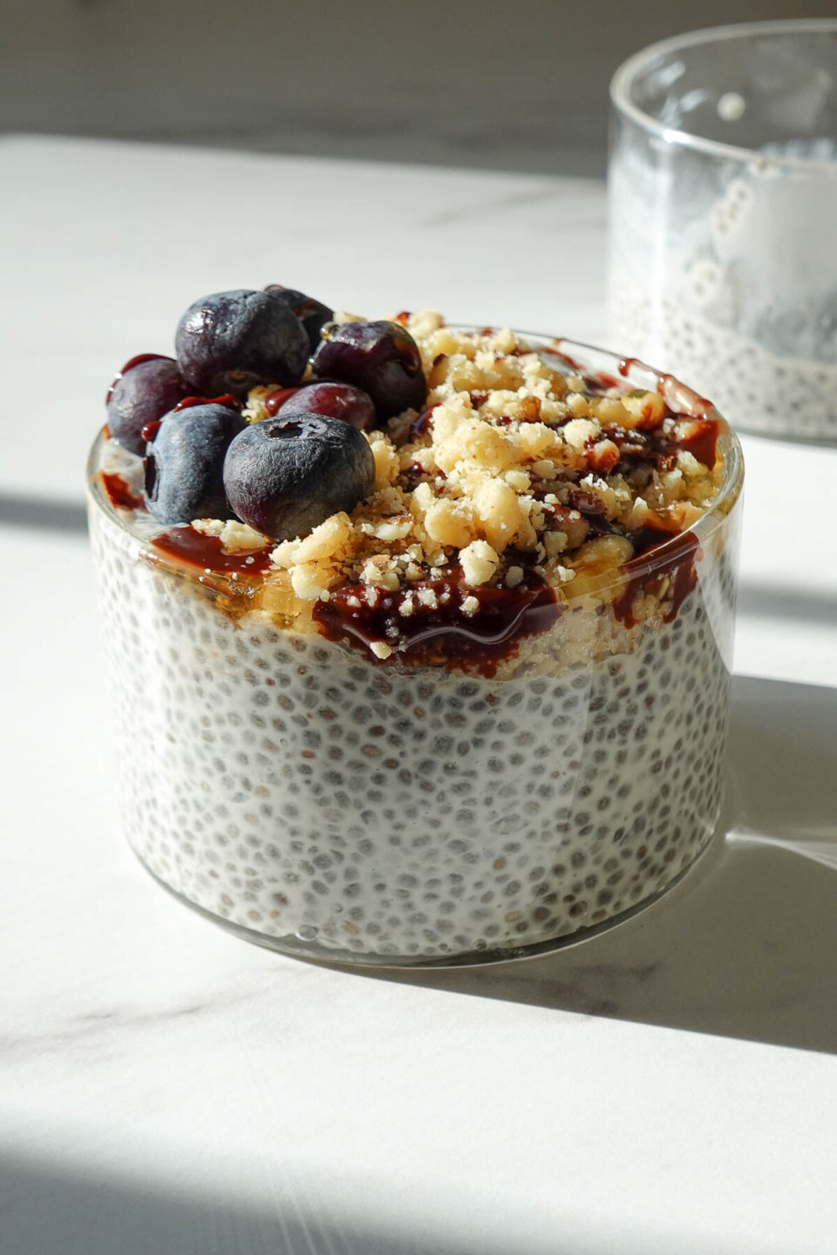 the best chia pudding for a healthy breakfast or snack topped with blueberries, chopped walnuts, and a drizzle of date syrup