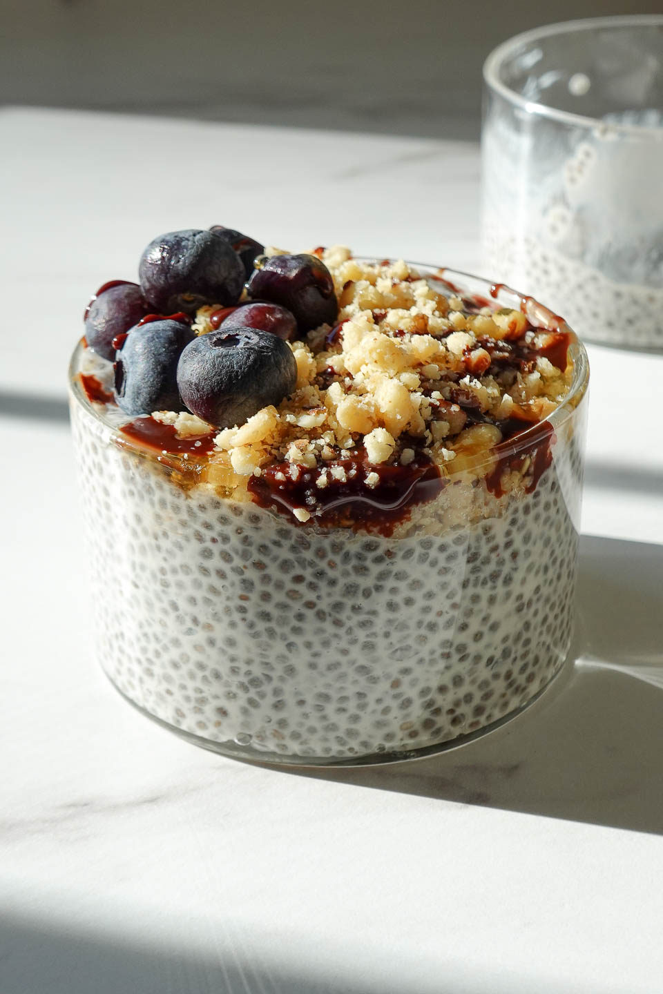 the best chia pudding for a healthy breakfast or snack topped with blueberries, chopped walnuts, and a drizzle of date syrup