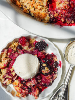 overhead shot of healthy berry crisp in a bowl topped with a scoop of vegan vanilla ice cream