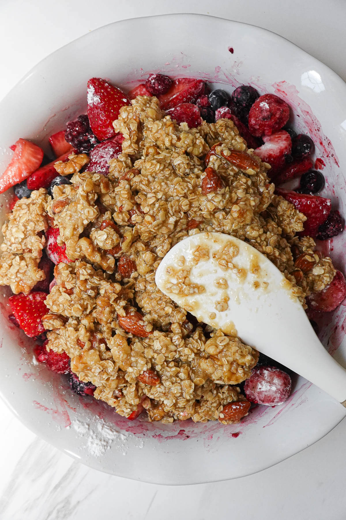Spreading the crisp mixture on top of the fruit.