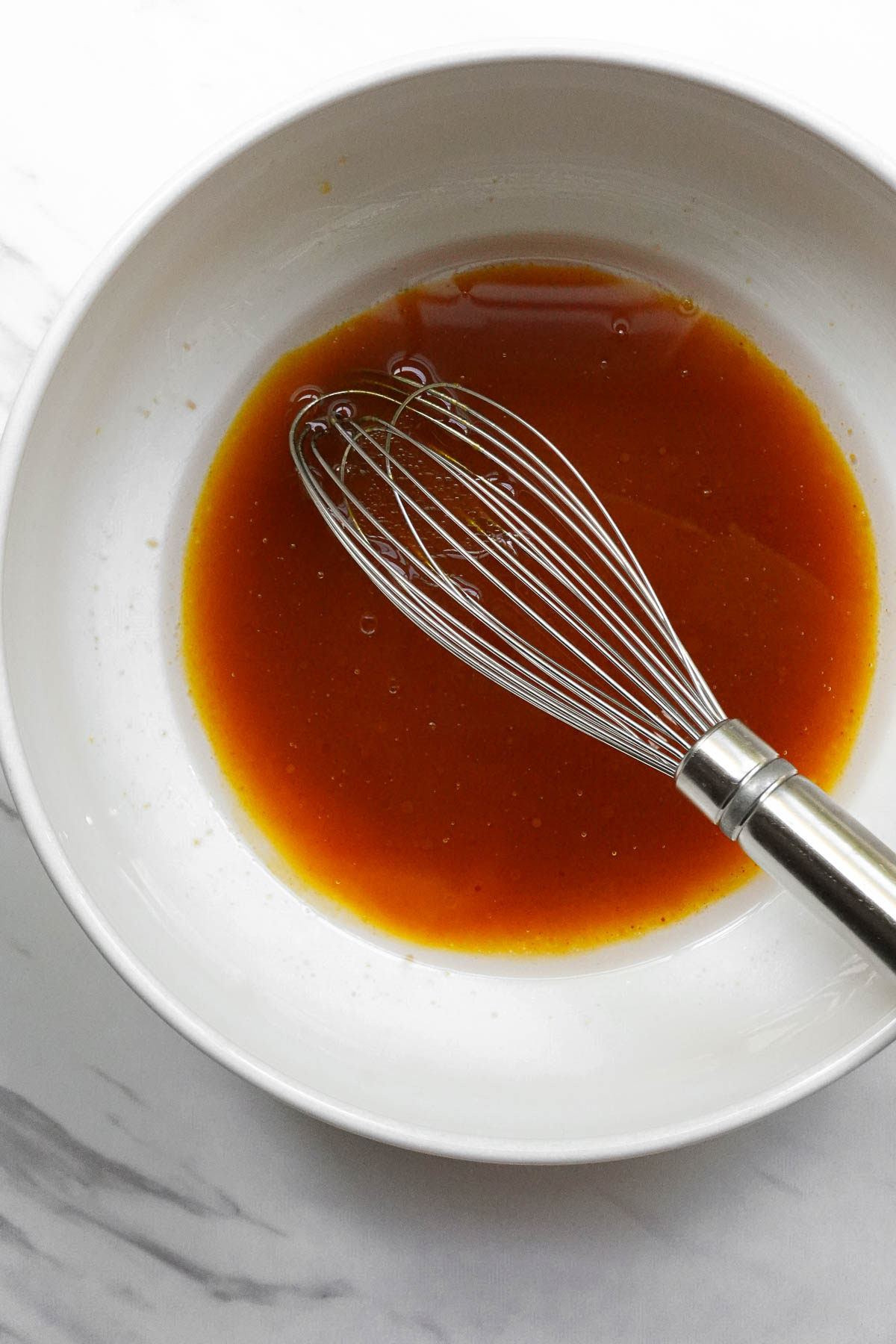 Whisking pumpkin puree, maple syrup, melted coconut oil, and vanilla for pumpkin spice granola.
