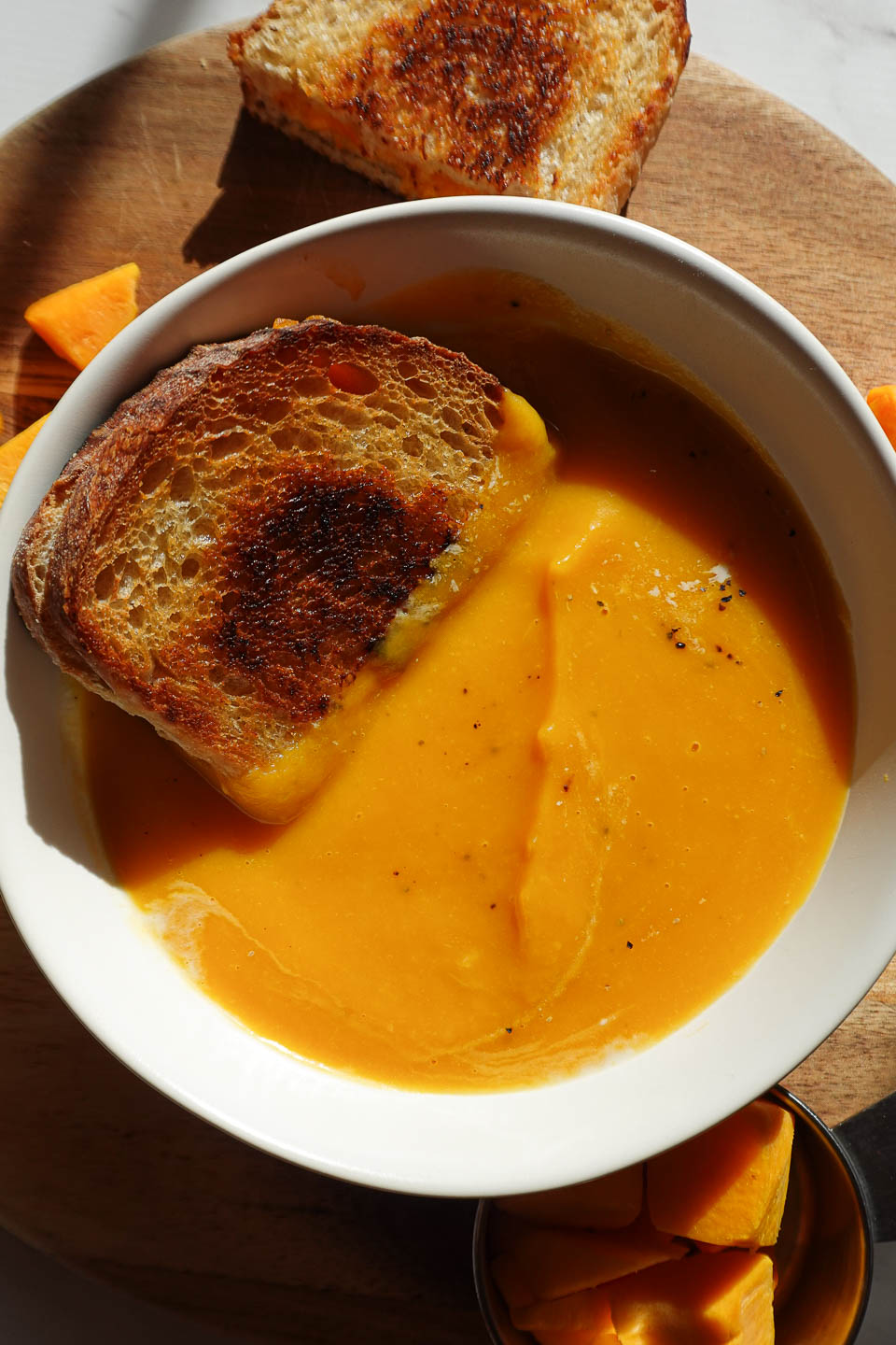 Vegan grilled cheese sandwich dipped into creamy butternut squash soup.