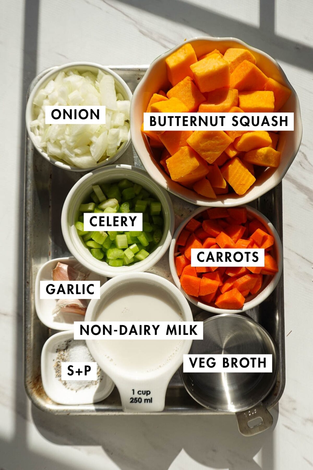 Ingredients for vegan butternut squash soup including butternut squash, onion, carrots, celery, garlic, and vegetable stock