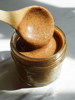 Creamy homemade hazelnut butter spooned into a glass jar.