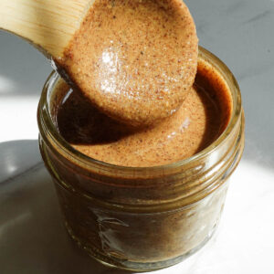 Creamy homemade hazelnut butter spooned into a glass jar.