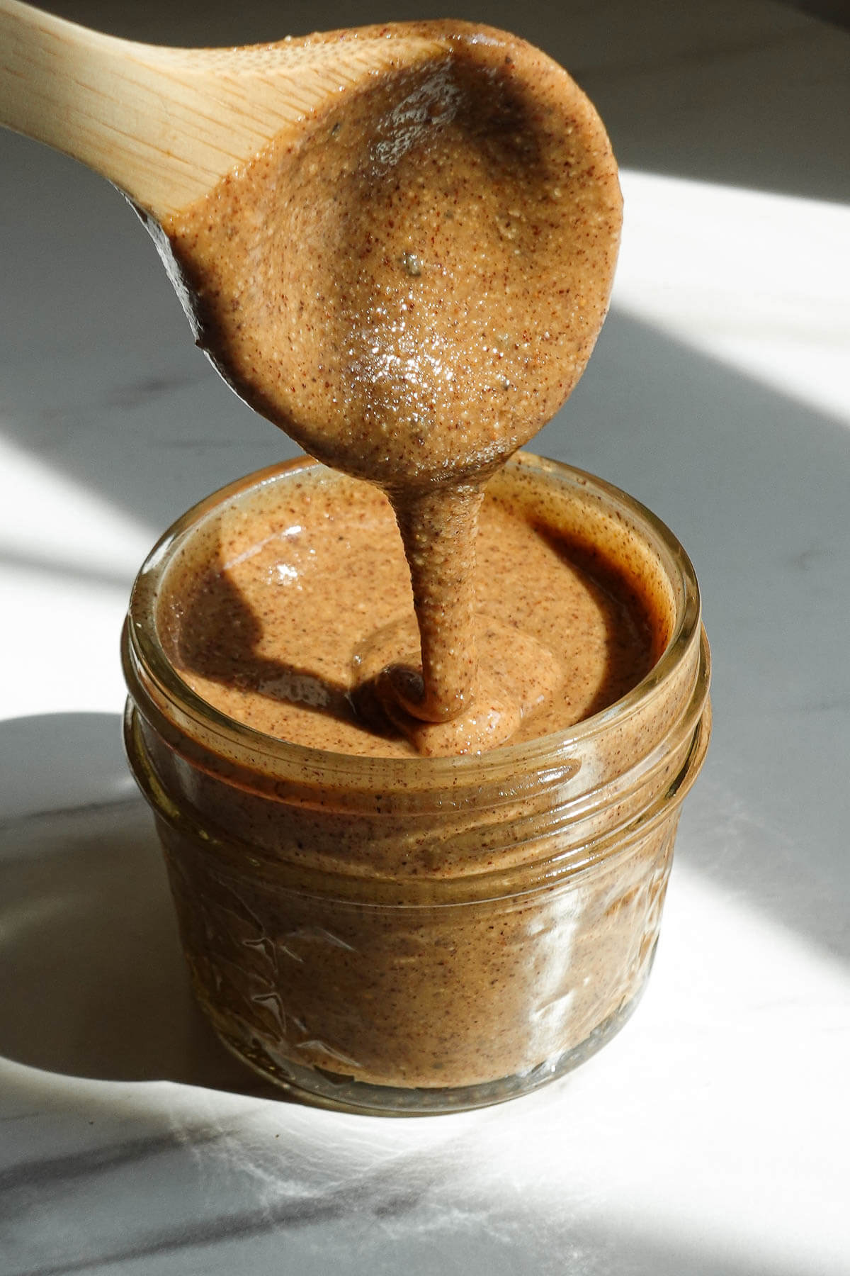 Homemade hazelnut butter spooned into a glass jar.
