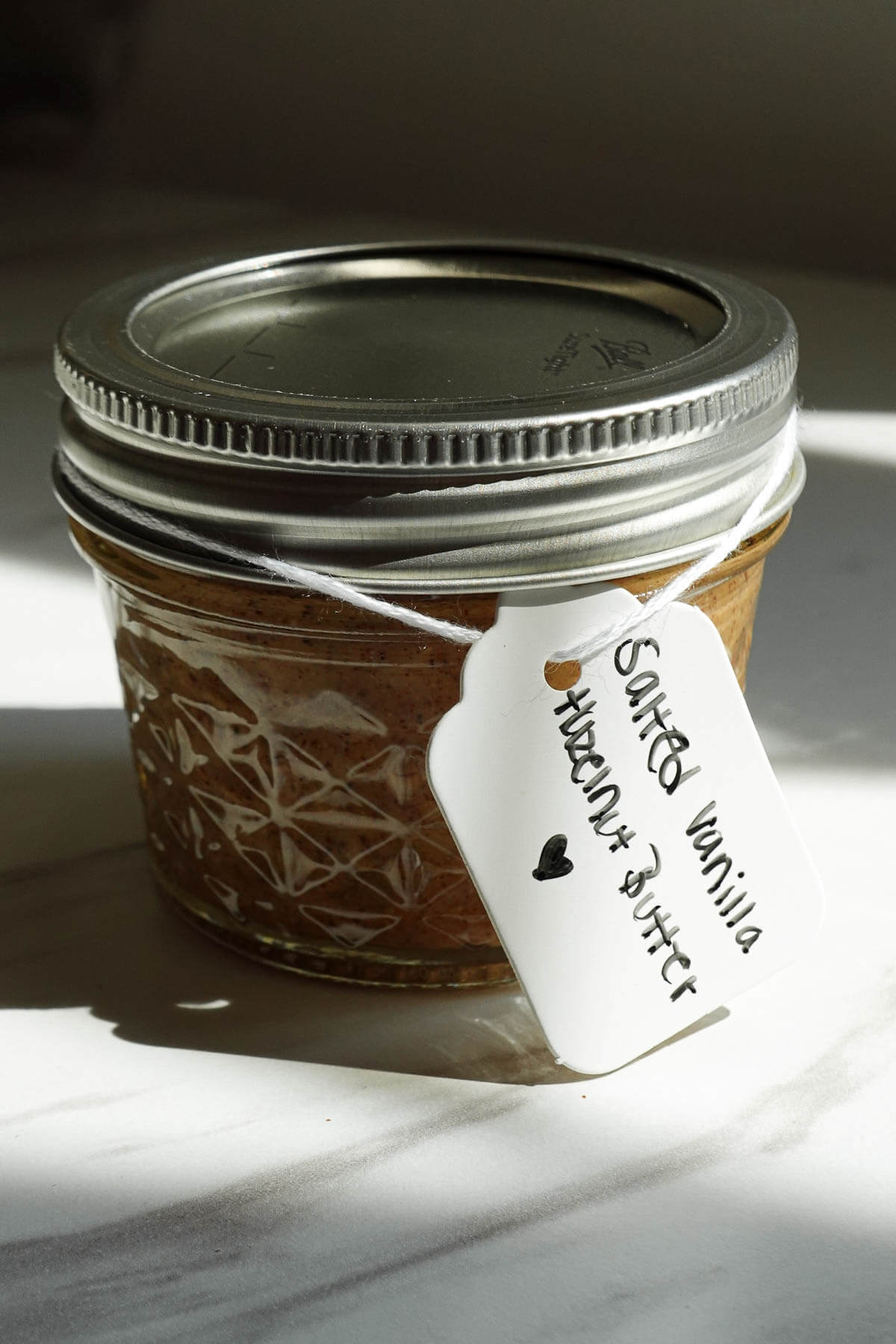 Salted vanilla hazelnut butter in a glass jar with a gift tag.