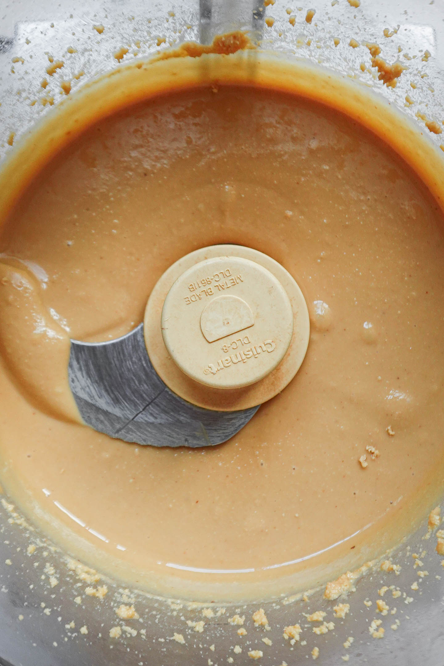 Thick peanut butter mixture blending into smooth texture step by step