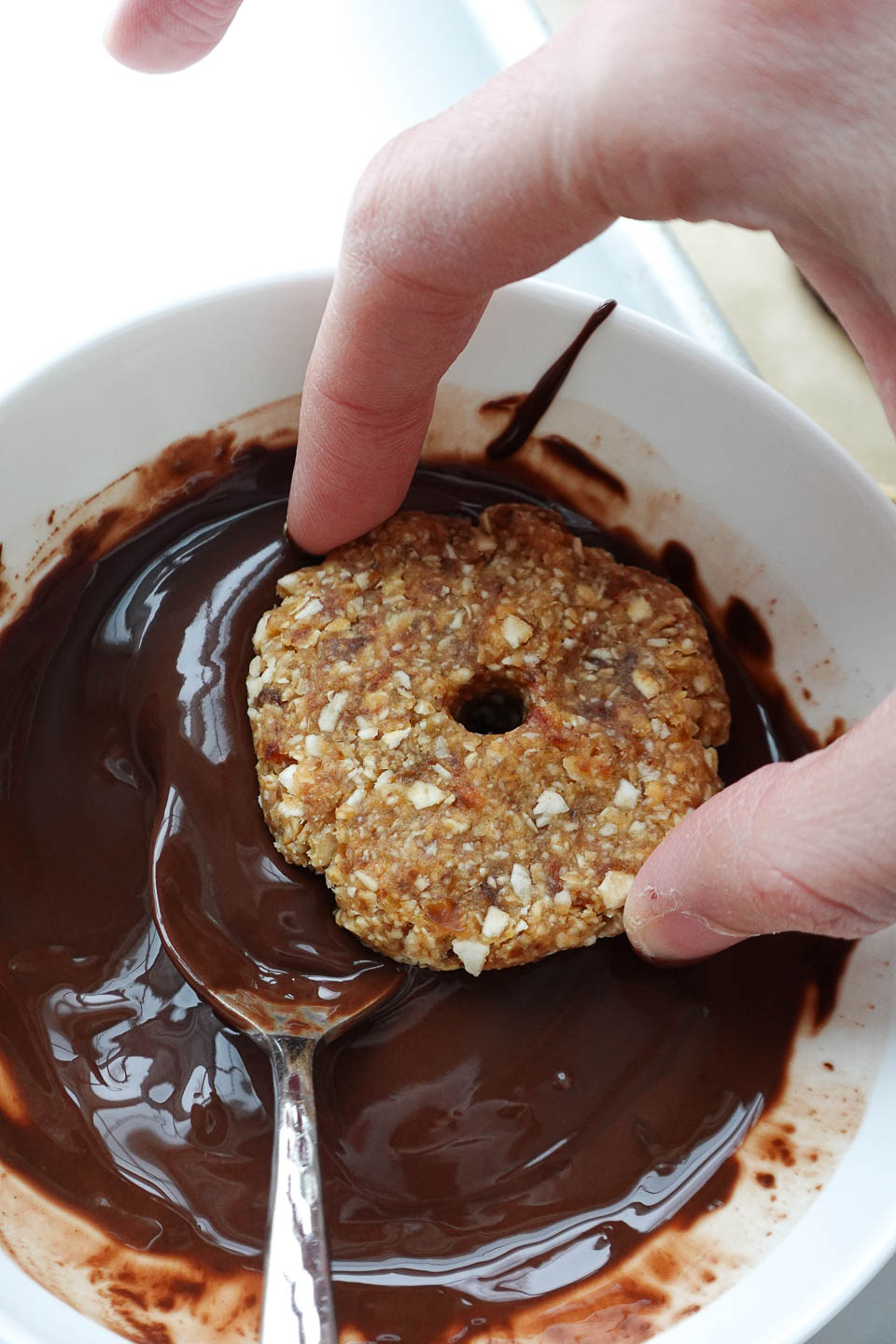 dipping samoas cookies into melted chocolate