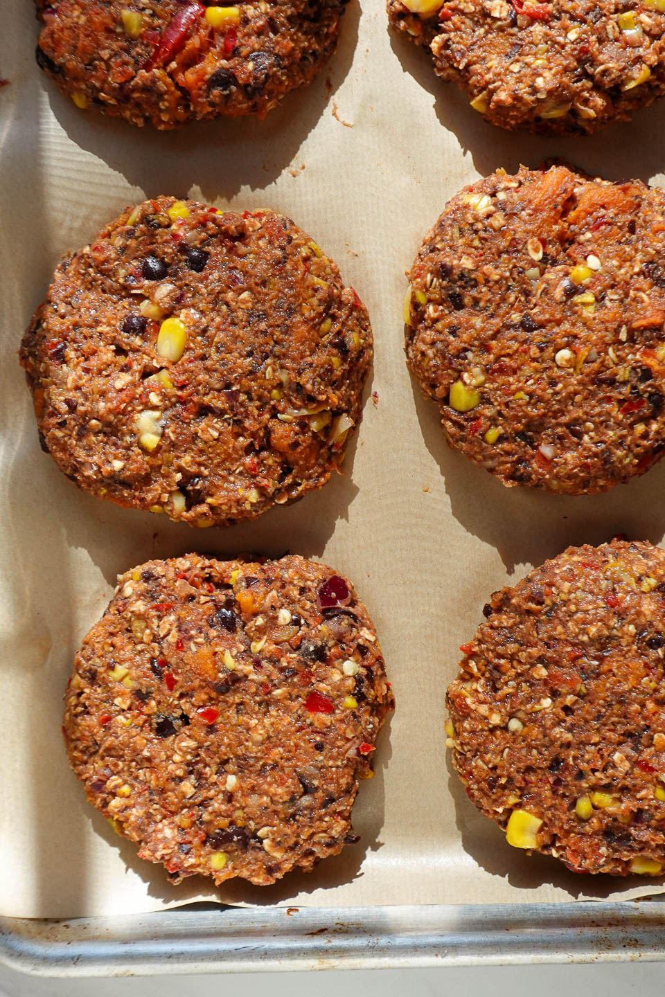 Uncooked sweet potato veggie burger patties on a baking sheet