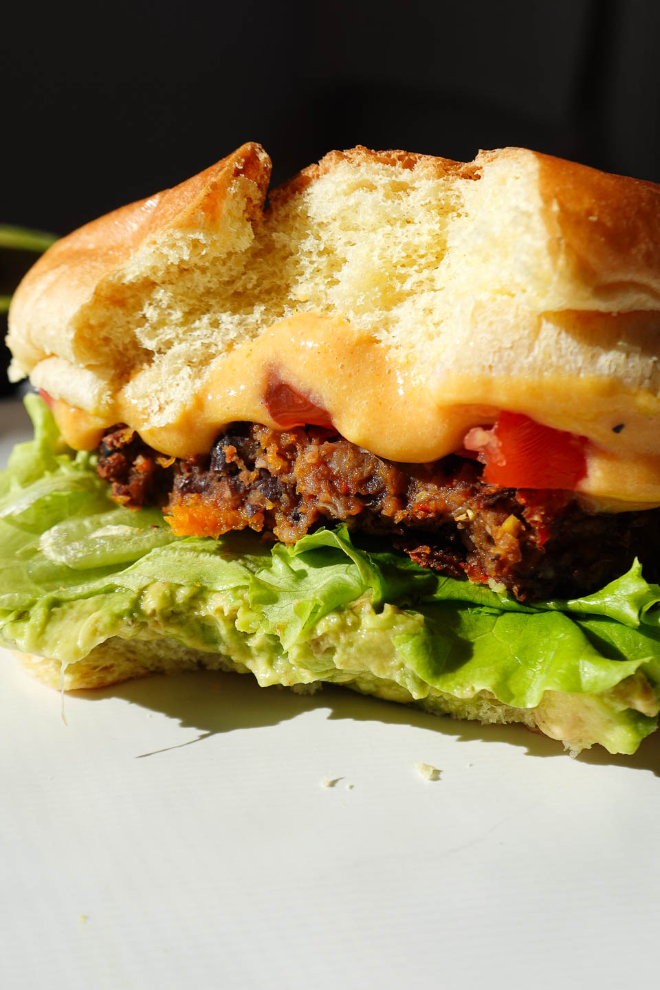 Vegan black bean and sweet potato veggie burgers served on a bun with a bite taken out
