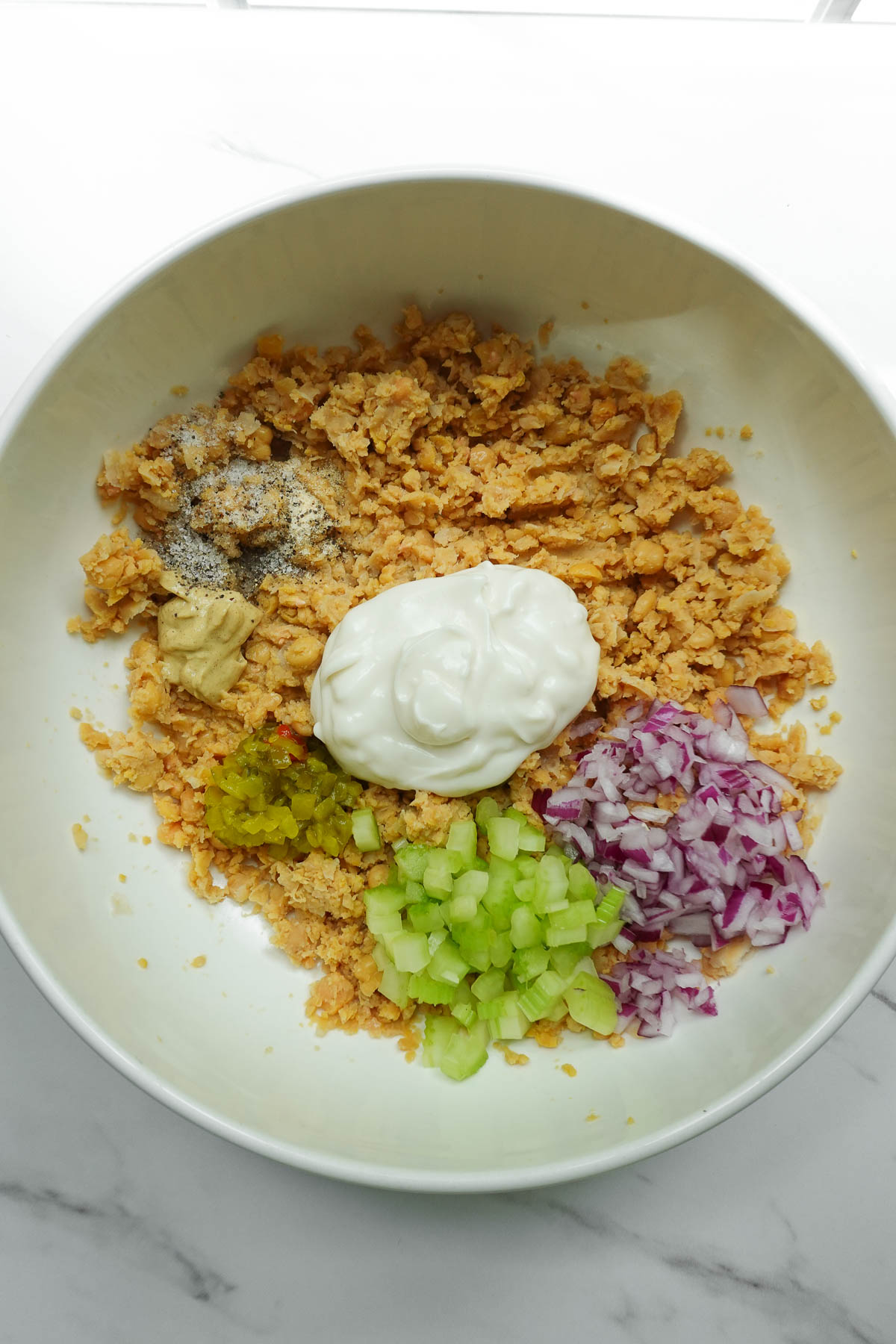 Vegan mayonnaise, celery, red onion, dijon mustard, relish, and seasonings added to mashed chickpeas.