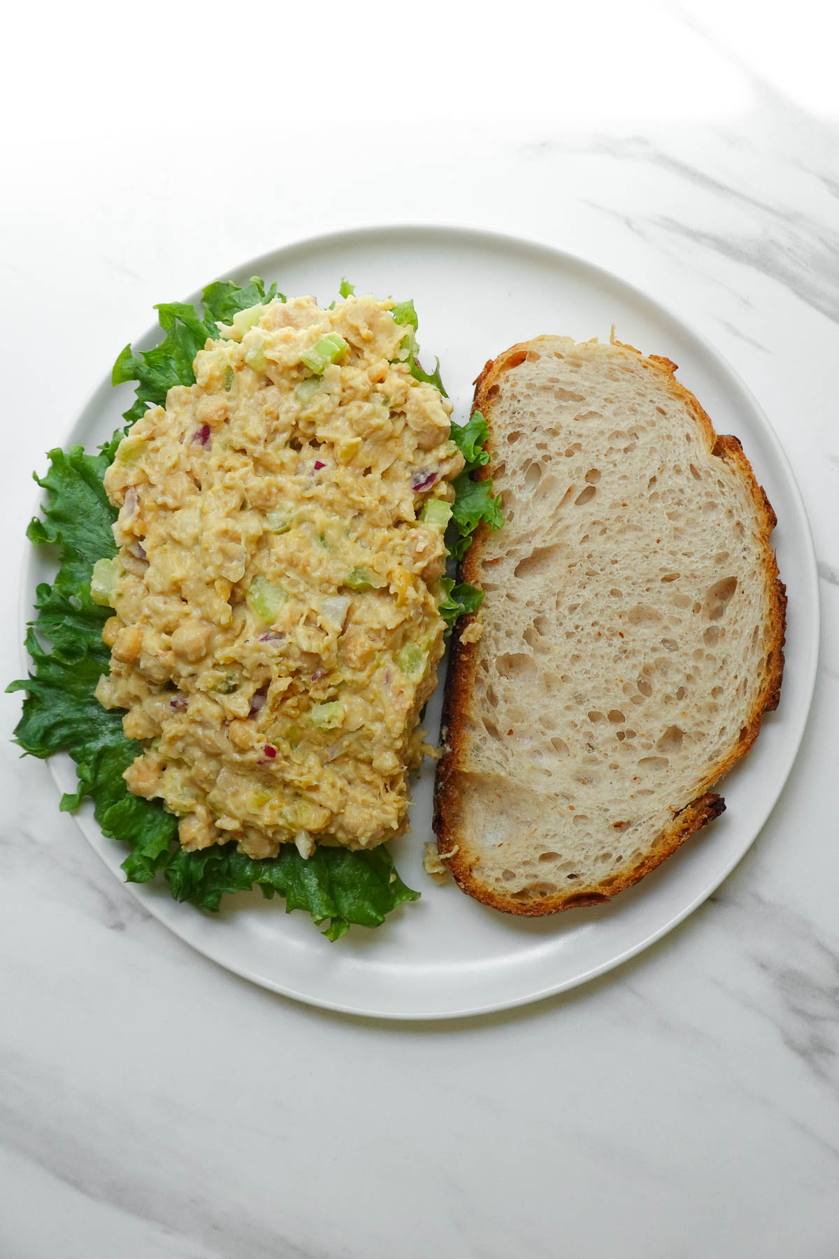 Chickpea salad spread onto slices of sourdough bread.