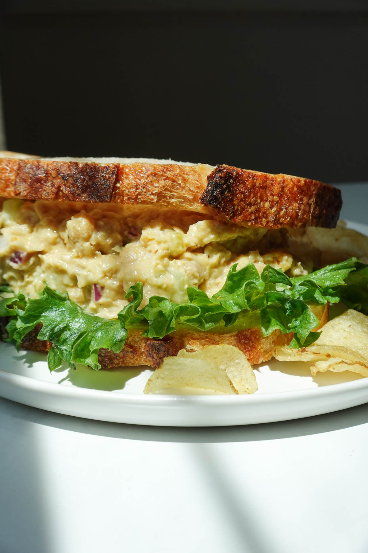 Close-up of creamy chickpea salad sandwich with lettuce.