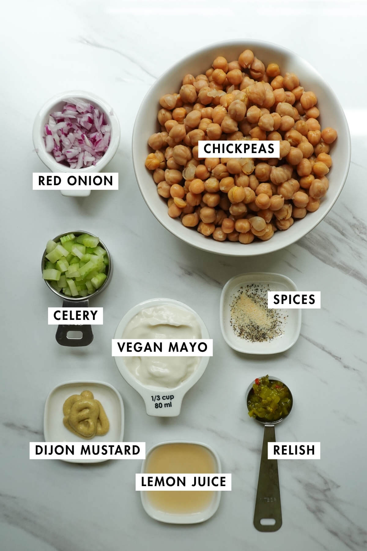 Ingredients for vegan chickpea salad sandwich including chickpeas, vegan mayonnaise, celery, red onion, lemon juice, dijon mustard, and dill pickle relish.
