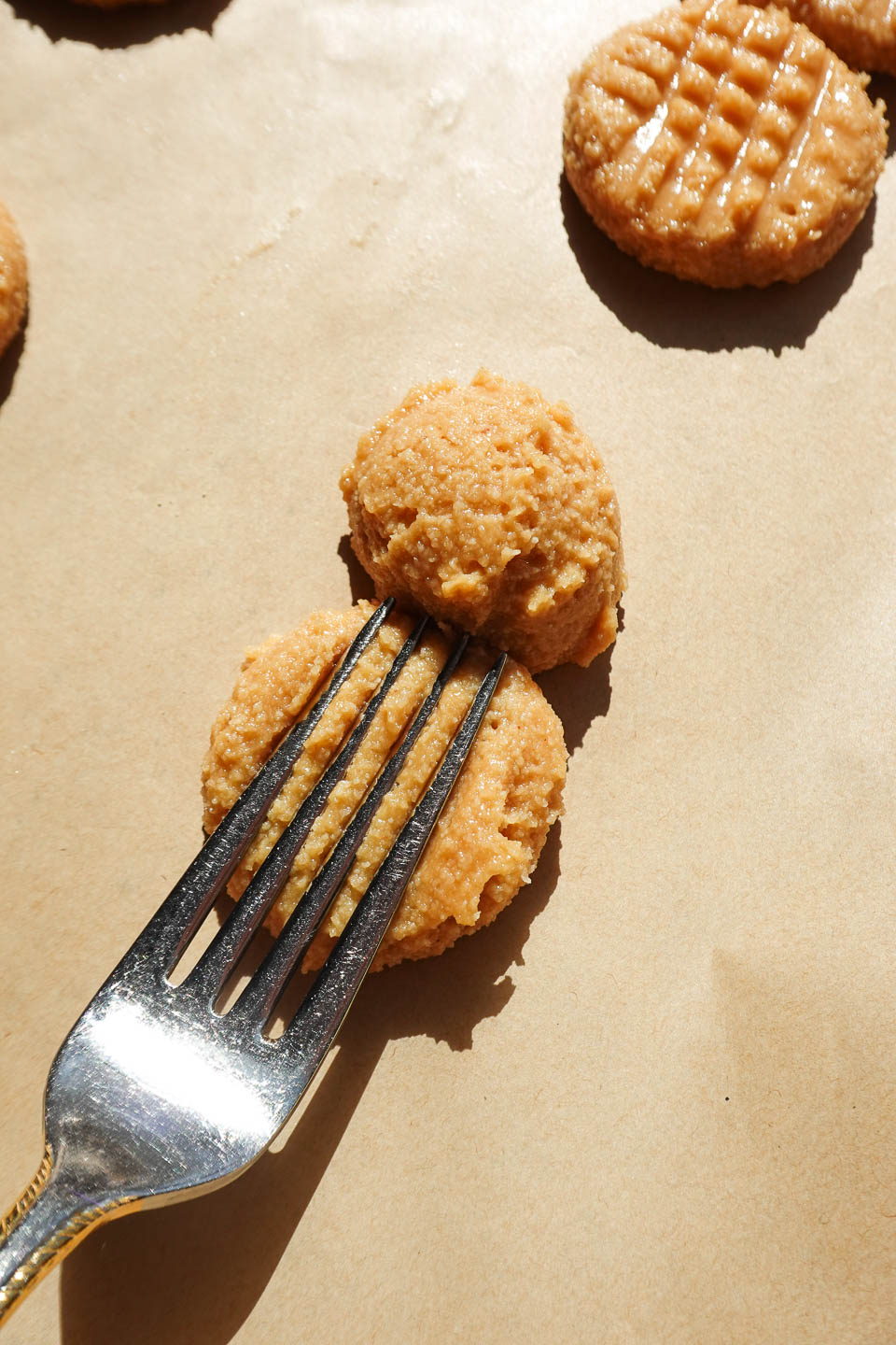 pressing peanut butter cookies with fork to create a hatch pattern