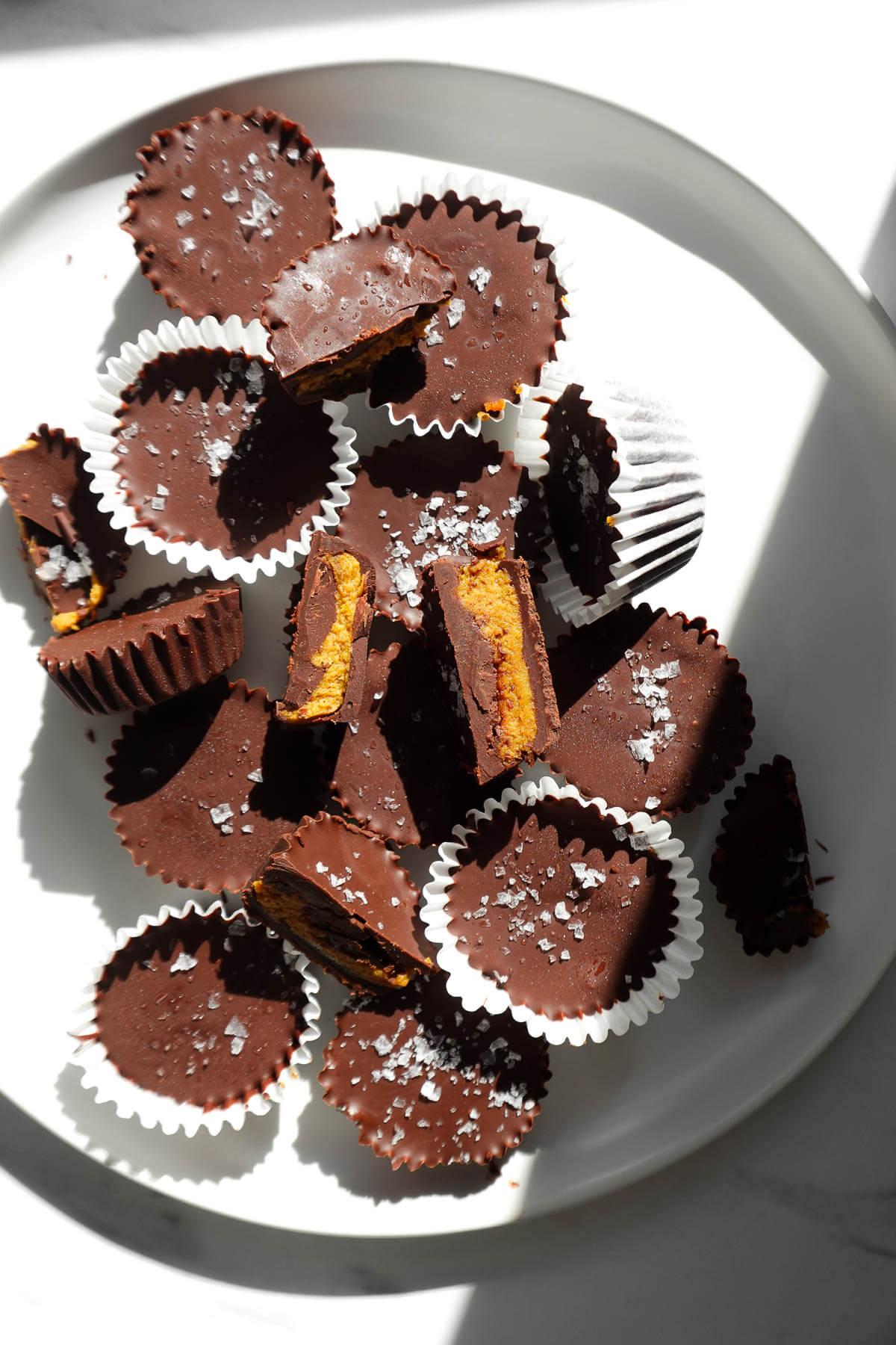 A plate full of pumpkin peanut butter cups with chocolate shells and pumpkin peanut butter filling.