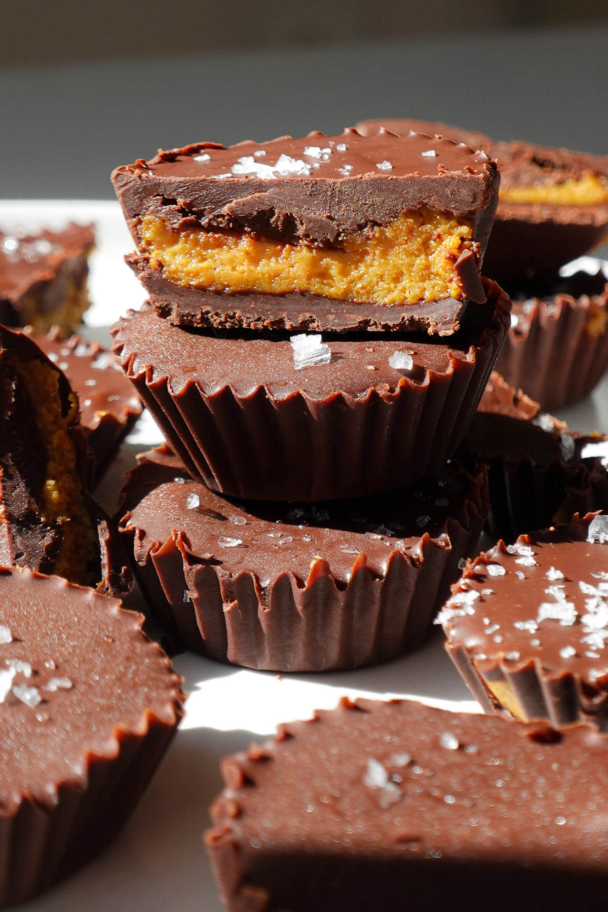 Pumpkin peanut butter cups stacked to show the chocolate coating and pumpkin peanut butter filling.