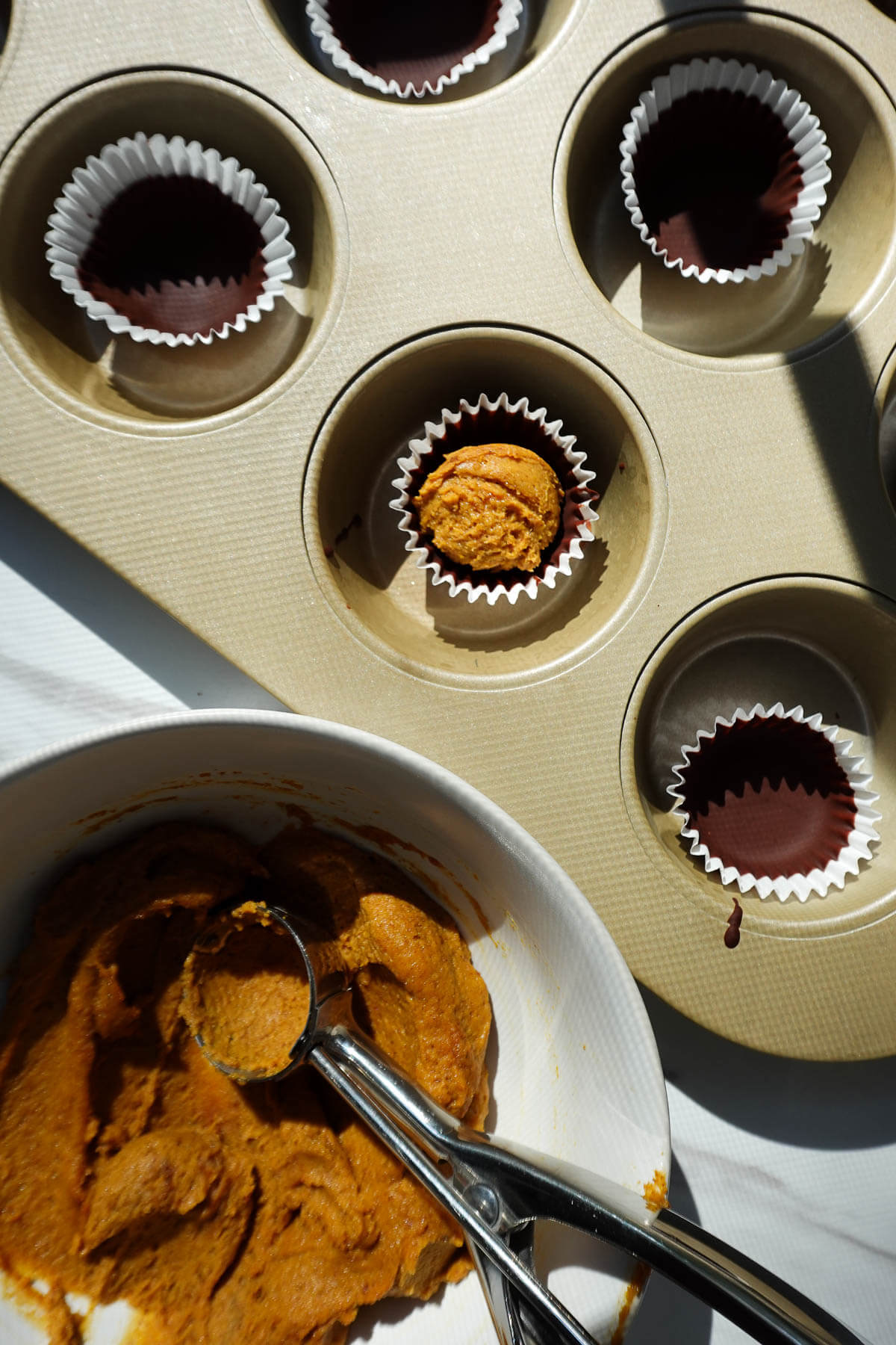 Adding the filling into the chocolate shell to make pumpkin peanut butter cups.