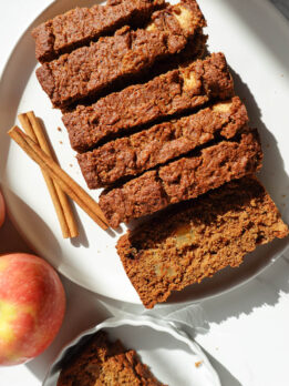 healthy apple bread sliced on a plate with apples in the background