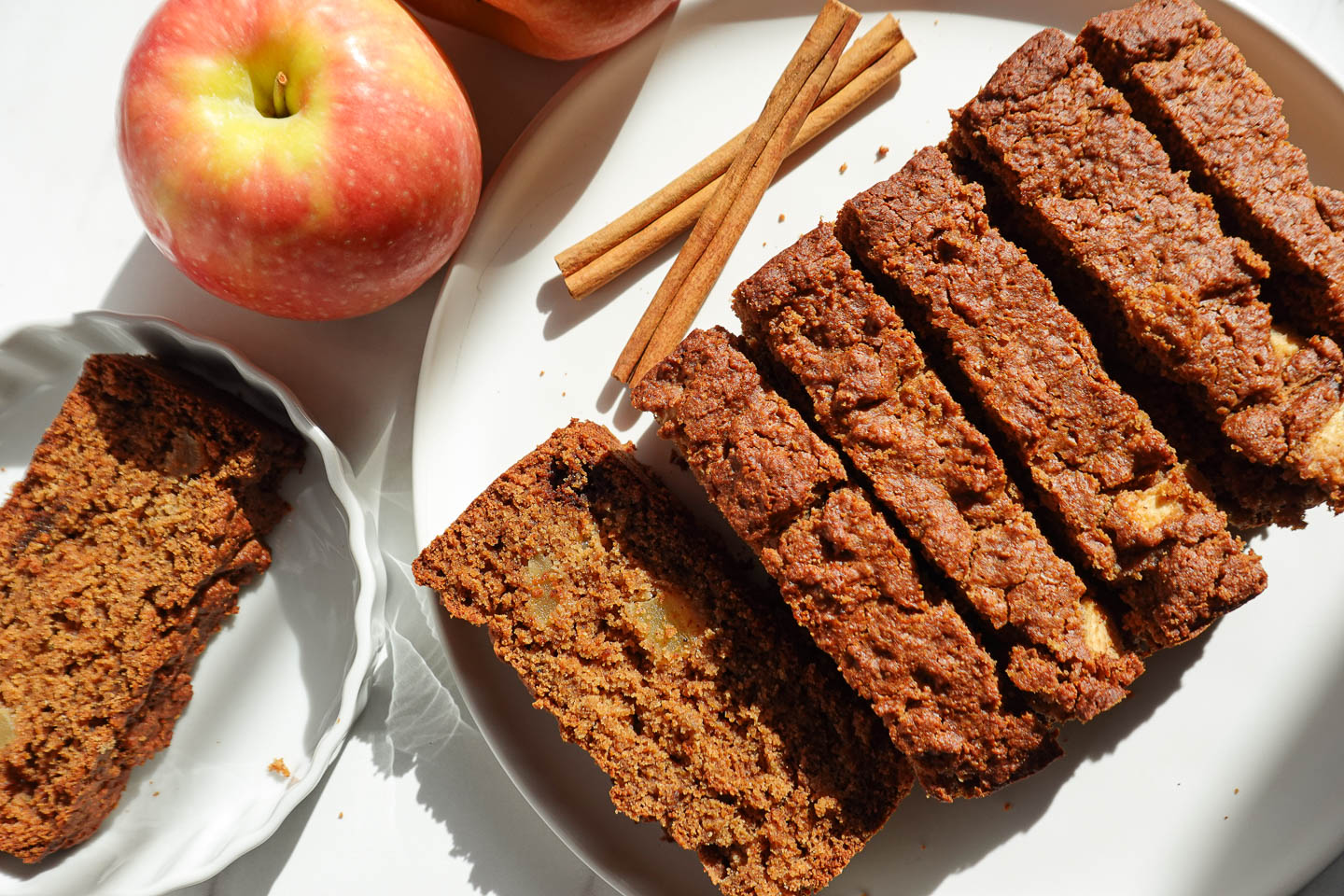 healthy apple bread sliced on a plate with apples in the background
