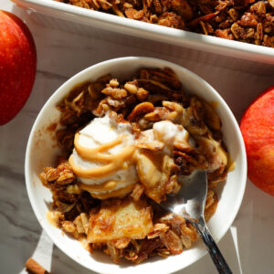 Healthy apple crisp served in a bowl topped with vanilla ice cream.