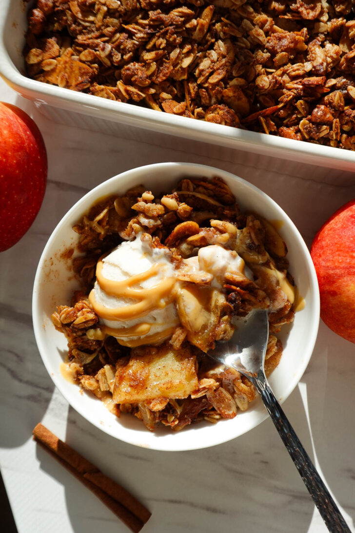 Healthy apple crisp with a golden oat and nut topping, served with vanilla ice cream.