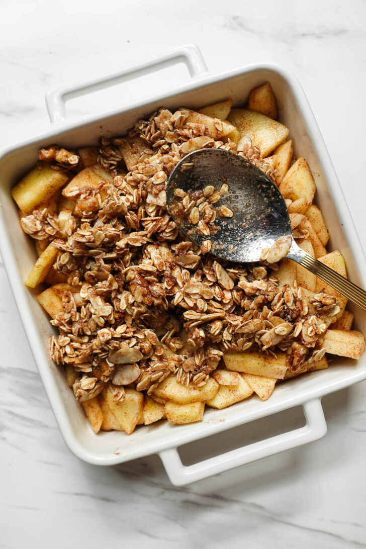 Apple filling covered with crisp topping in a baking dish before baking.