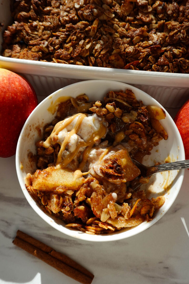 A bowl of homemade apple crisp topped with vanilla ice cream.