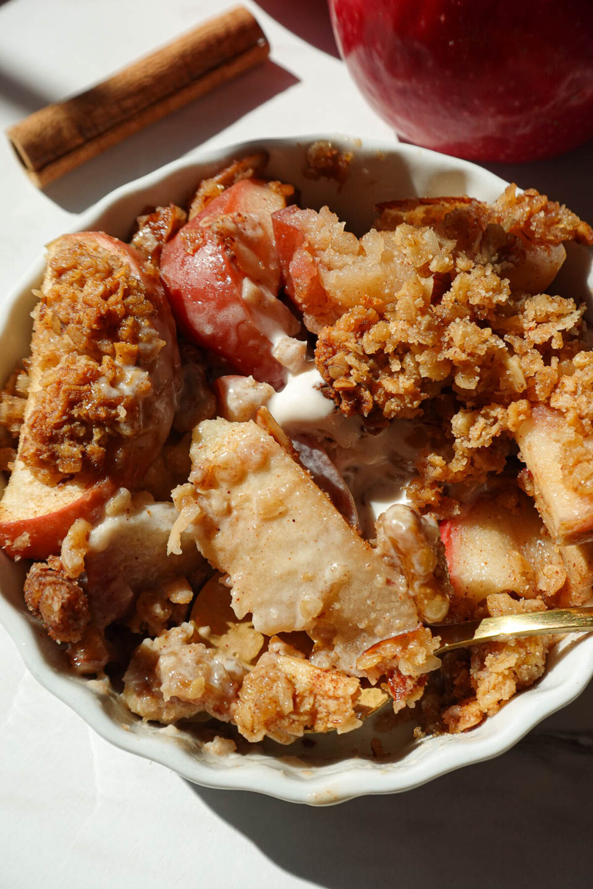 close up of healthy apple crisp served in a bowl with vanilla ice cream