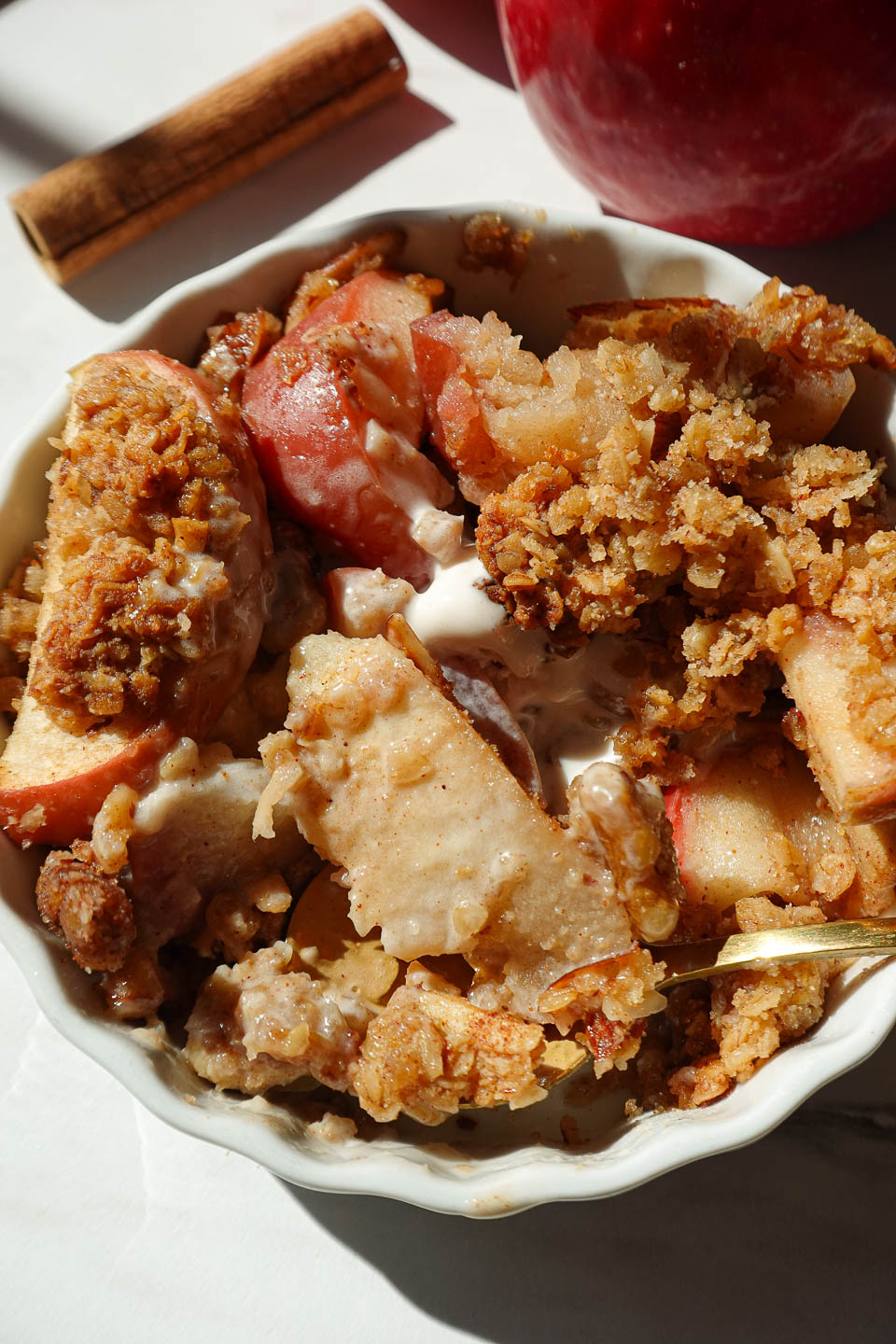 close up of healthy apple crisp served in a bowl with vanilla ice cream