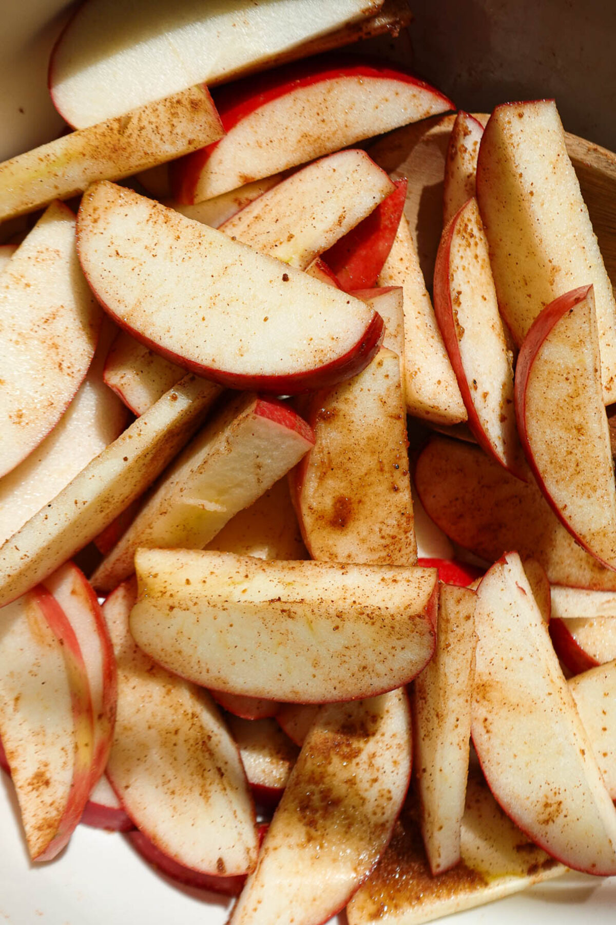 Sliced apples tossed with cinnamon and sugar in a baking dish