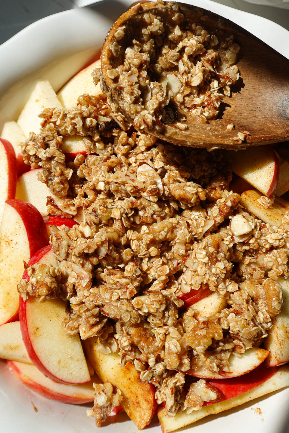 Sprinkling crisp topping over spiced apples before baking