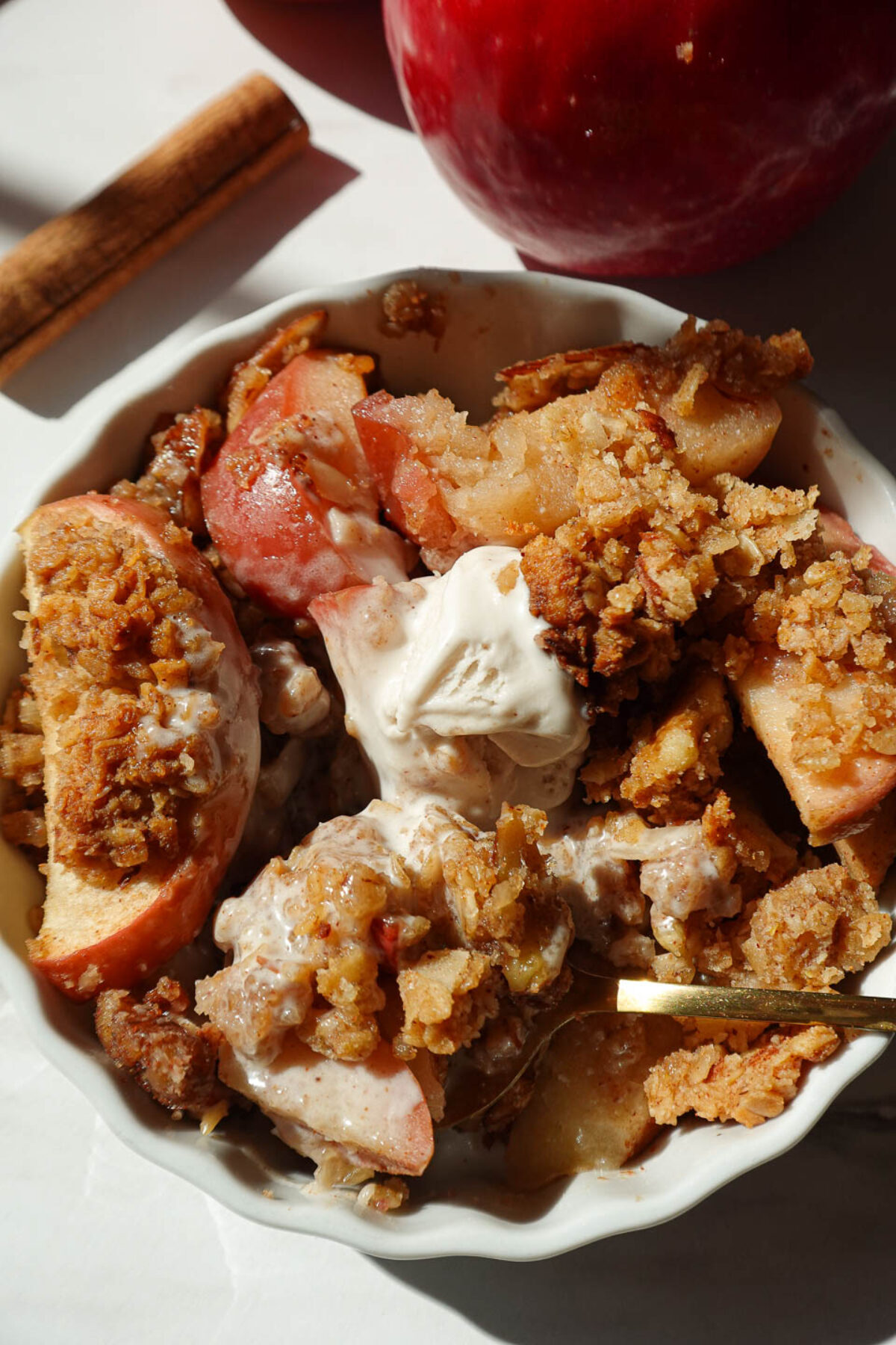 close up of vegan apple crisp served in a bowl with vanilla ice cream