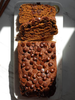 Vegan and gluten-free pumpkin bread on a marble plate with two slices.