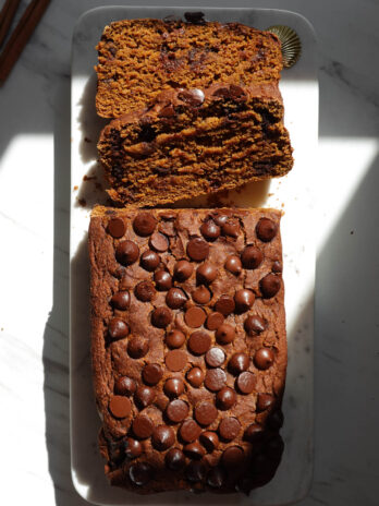 Vegan and gluten-free pumpkin bread on a marble plate with two slices.