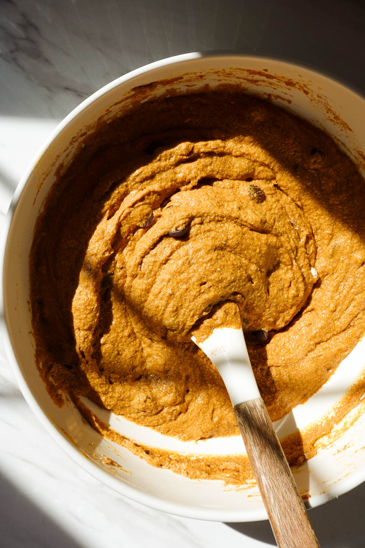 Folding chocolate chips into pumpkin bread batter.