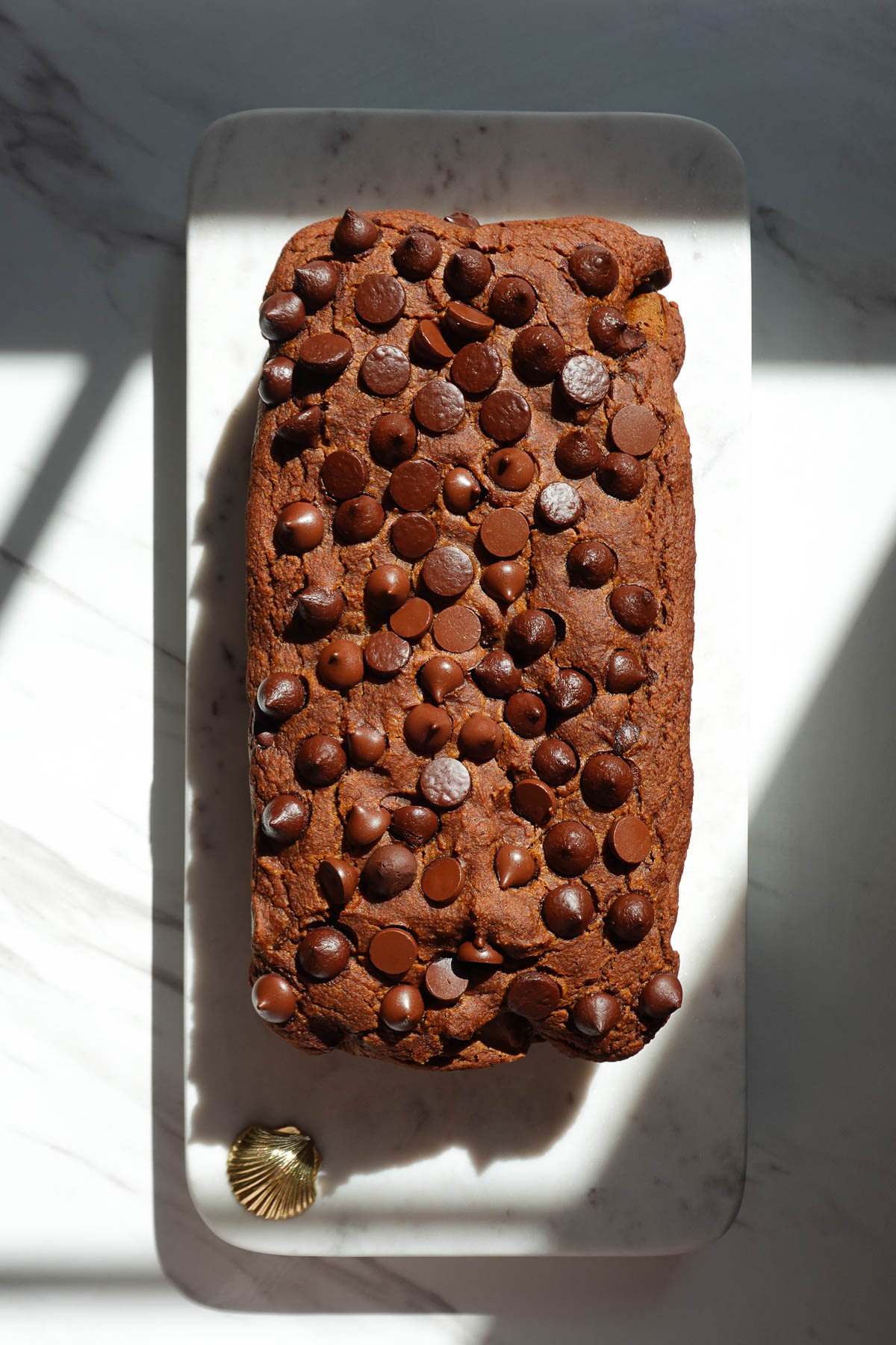 Freshly baked loaf of vegan pumpkin bread topped with chocolate chips.