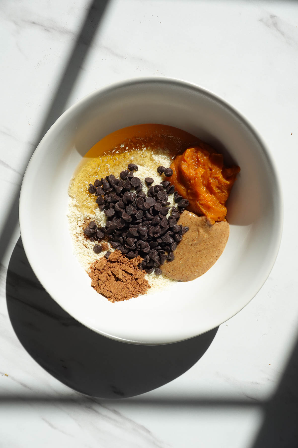 Ingredients for vegan pumpkin cookie dough in a mixing bowl.
