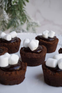 hot chocolate cookie cups topped with marshmallows and a vegan chocolate ganache
