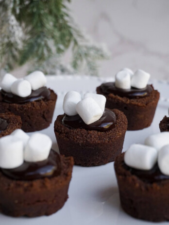 hot chocolate cookie cups topped with marshmallows and a vegan chocolate ganache