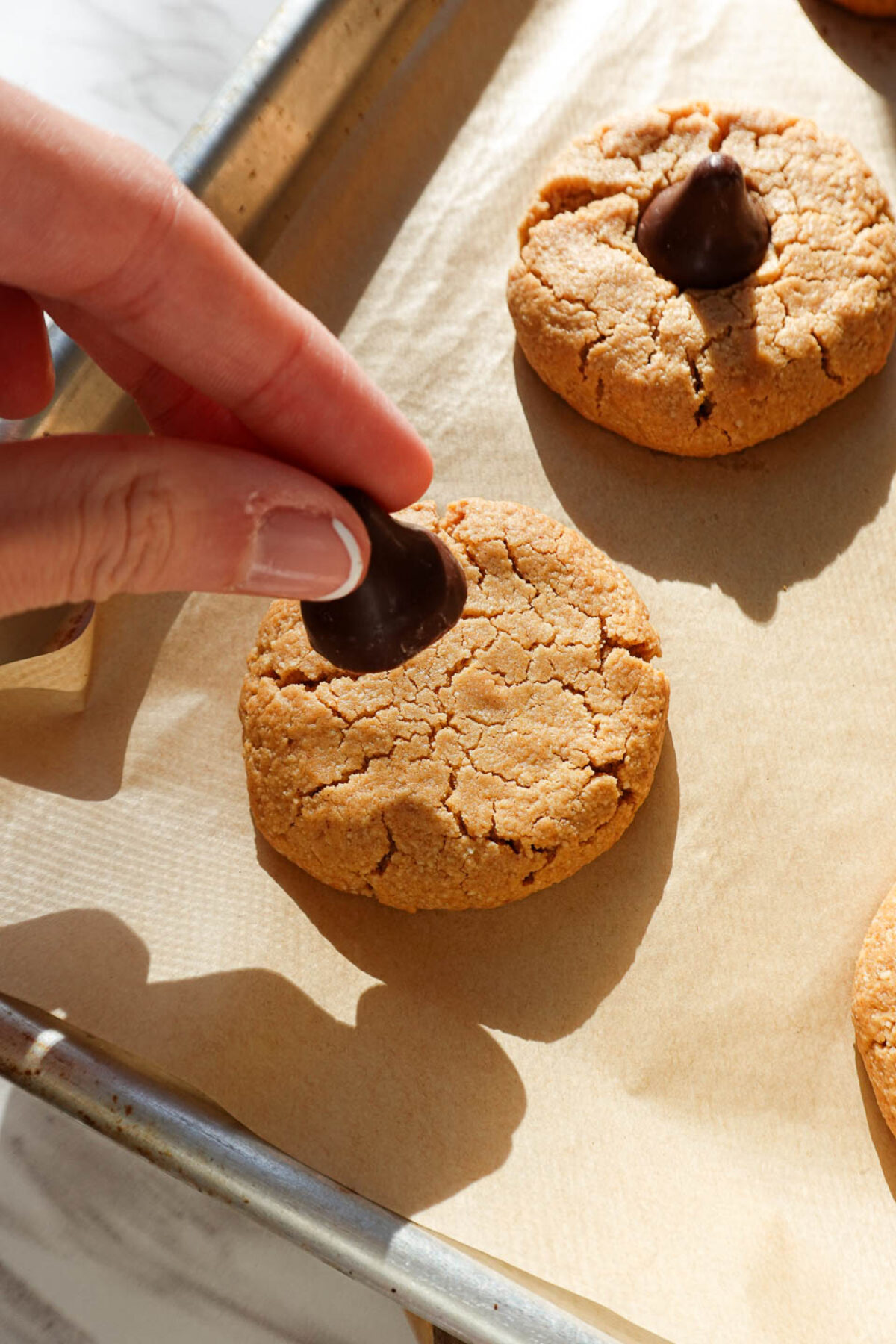 placing vegan chocolate kiss on peanut butter blossom