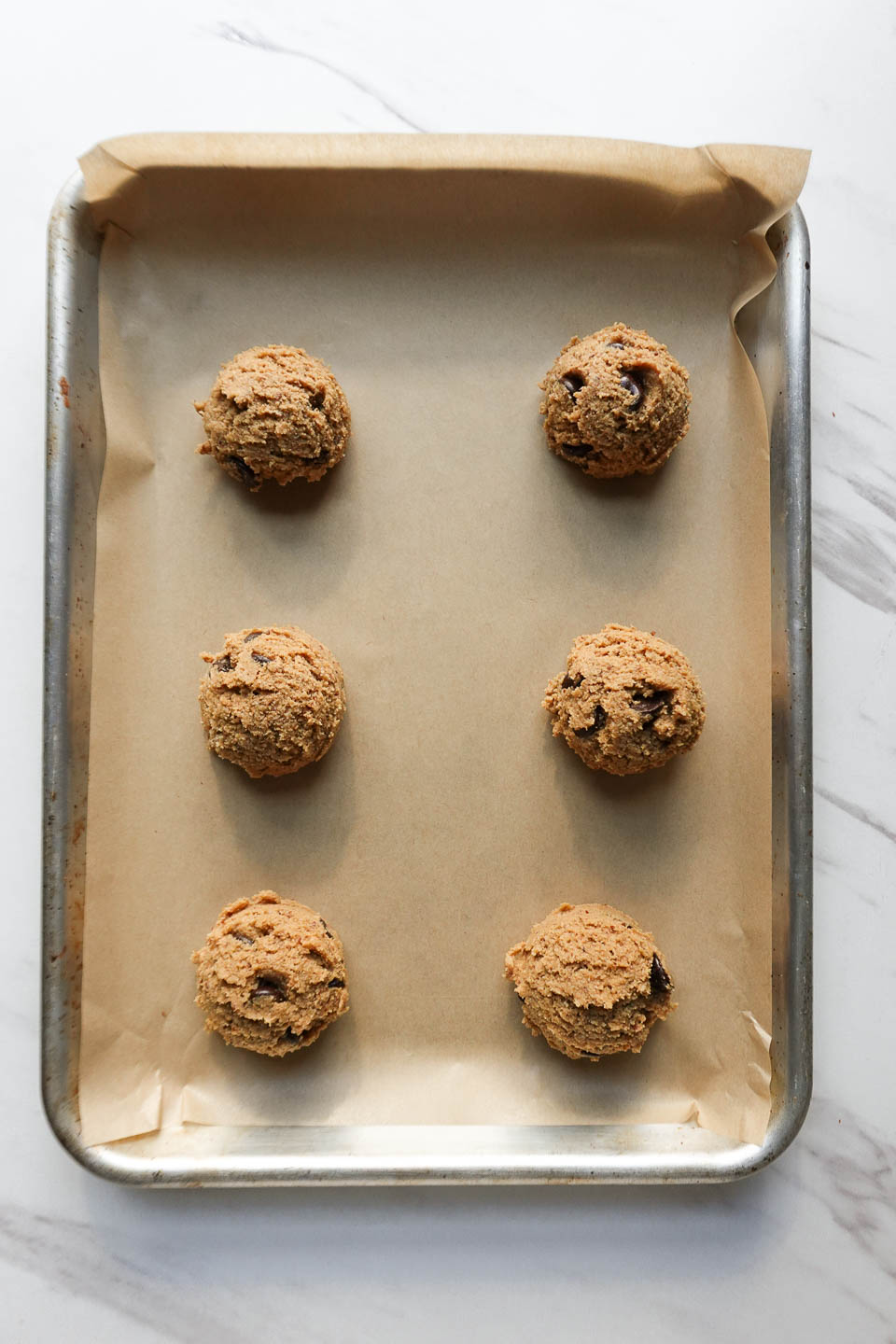 vegan chocolate chip cookies scooped onto a baking sheet