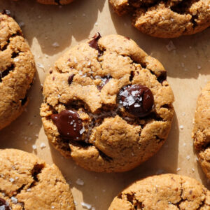 gluten-free and vegan chocolate chip cookies freshly baked on a baking sheet and sprinkled with flaky sea salt