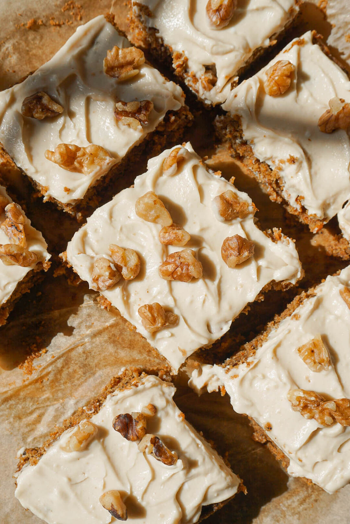 overhead shot of healthy carrot cake sliced and topped with vegan cream cheese frosting and chopped walnuts