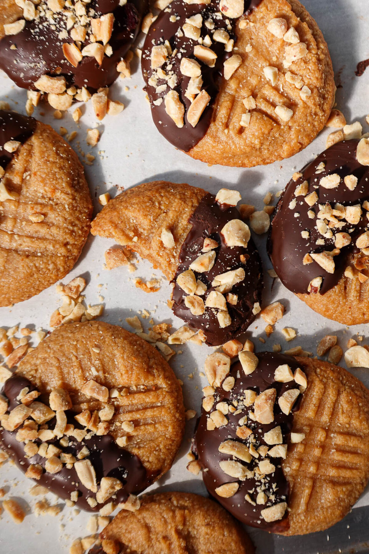 Overhead view of 3 ingredient peanut butter cookies half dipped in chocolate and sprinkled with chopped peanuts