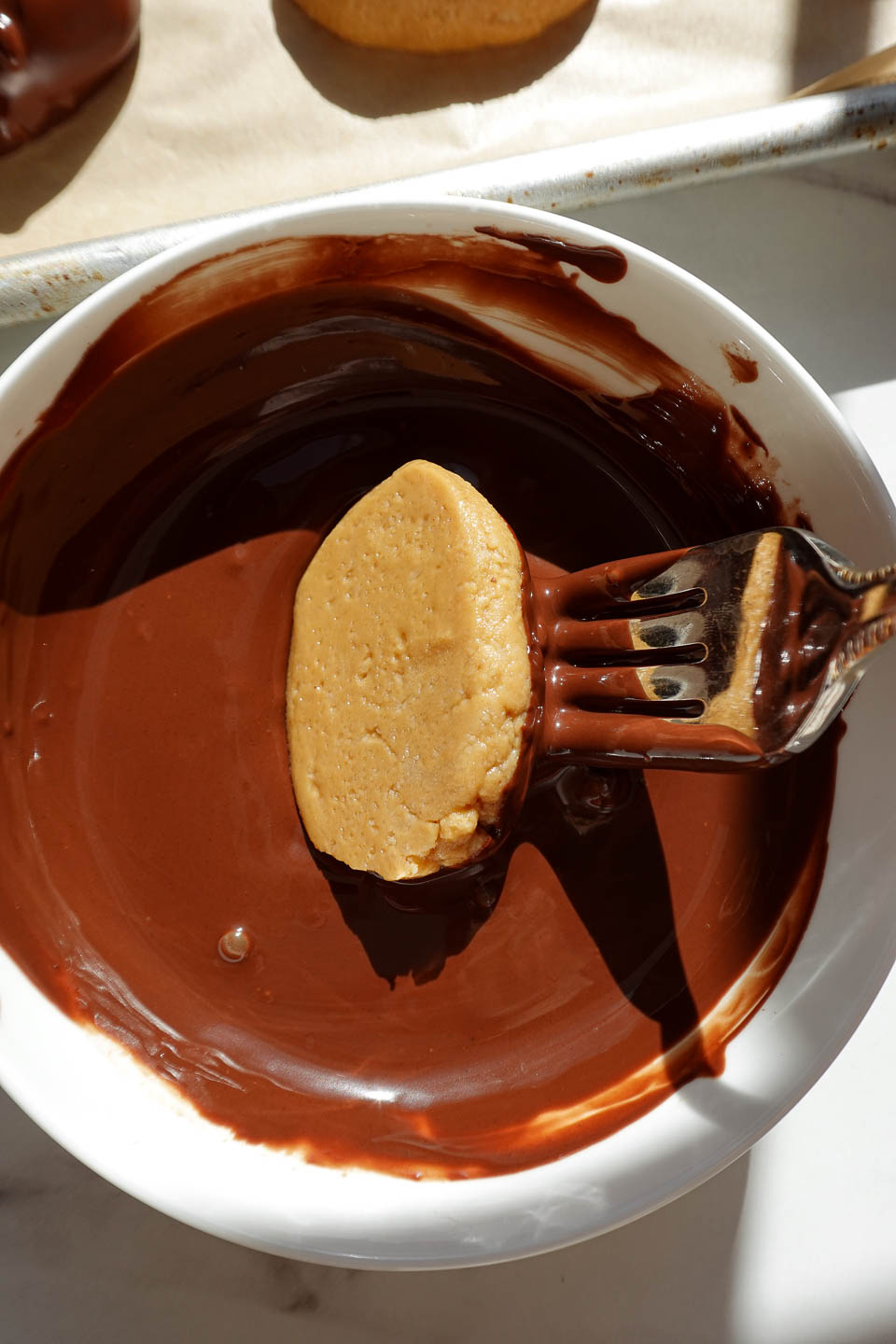 Dipping peanut butter eggs into melted dark chocolate using a fork